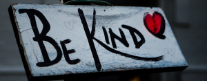 Be Kind written on wood with a red heart
